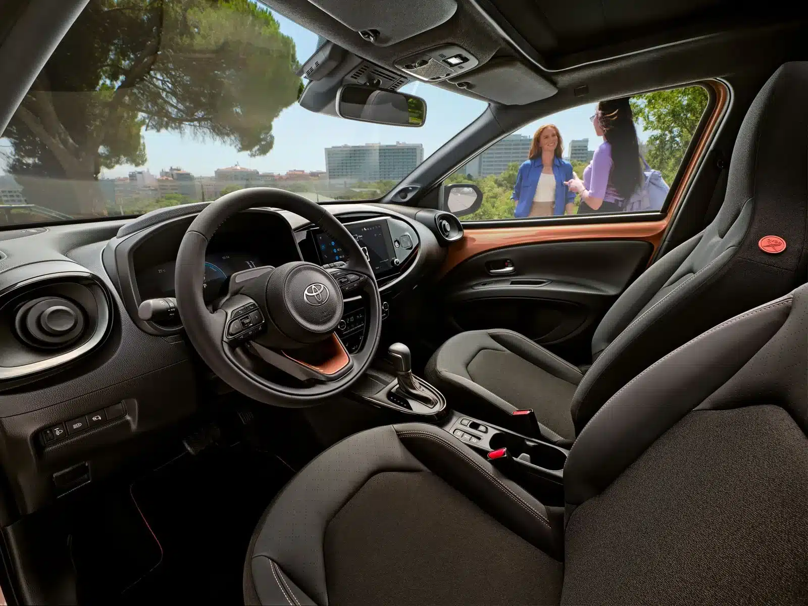 Innenraum des Toyota Aygo X Hybrid, Ansicht vom Fahrersitz mit Stadtblick durch das Fenster.