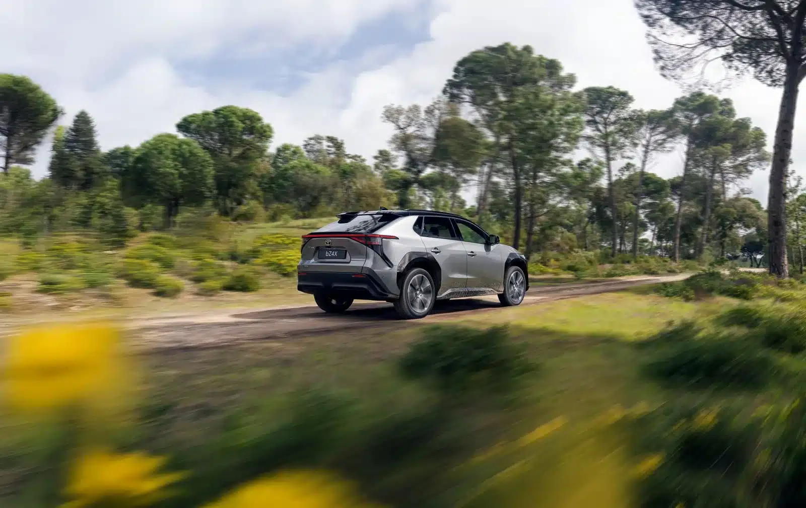 Toyota bZ4X SUV fährt auf einem Feldweg durch bewaldetes Gelände.