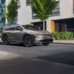 Toyota bZ4X Touring Elektro-SUV bei der Fahrt durch eine Stadt mit Bäumen und modernen Gebäuden im Hintergrund
