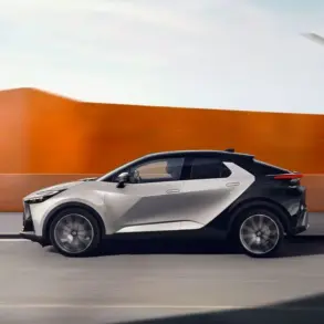 Toyota C-HR 2023 in Silber-Schwarz, seitlich fahrend vor moderner, orangefarbener Wand.