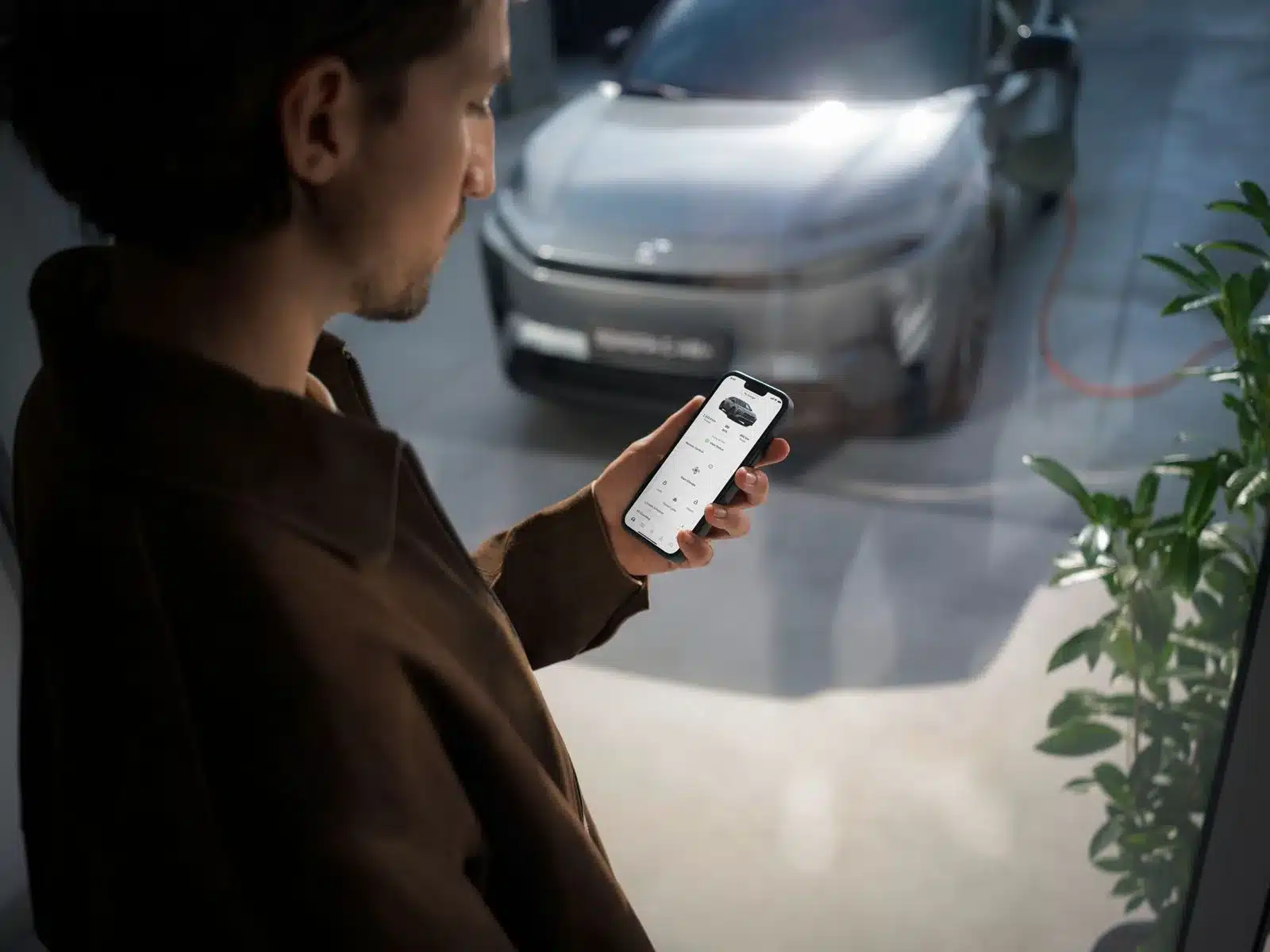 Mann mit Smartphone-App zur Steuerung und Überwachung des Ladevorgangs eines Toyota C-HR+ Elektroautos.
