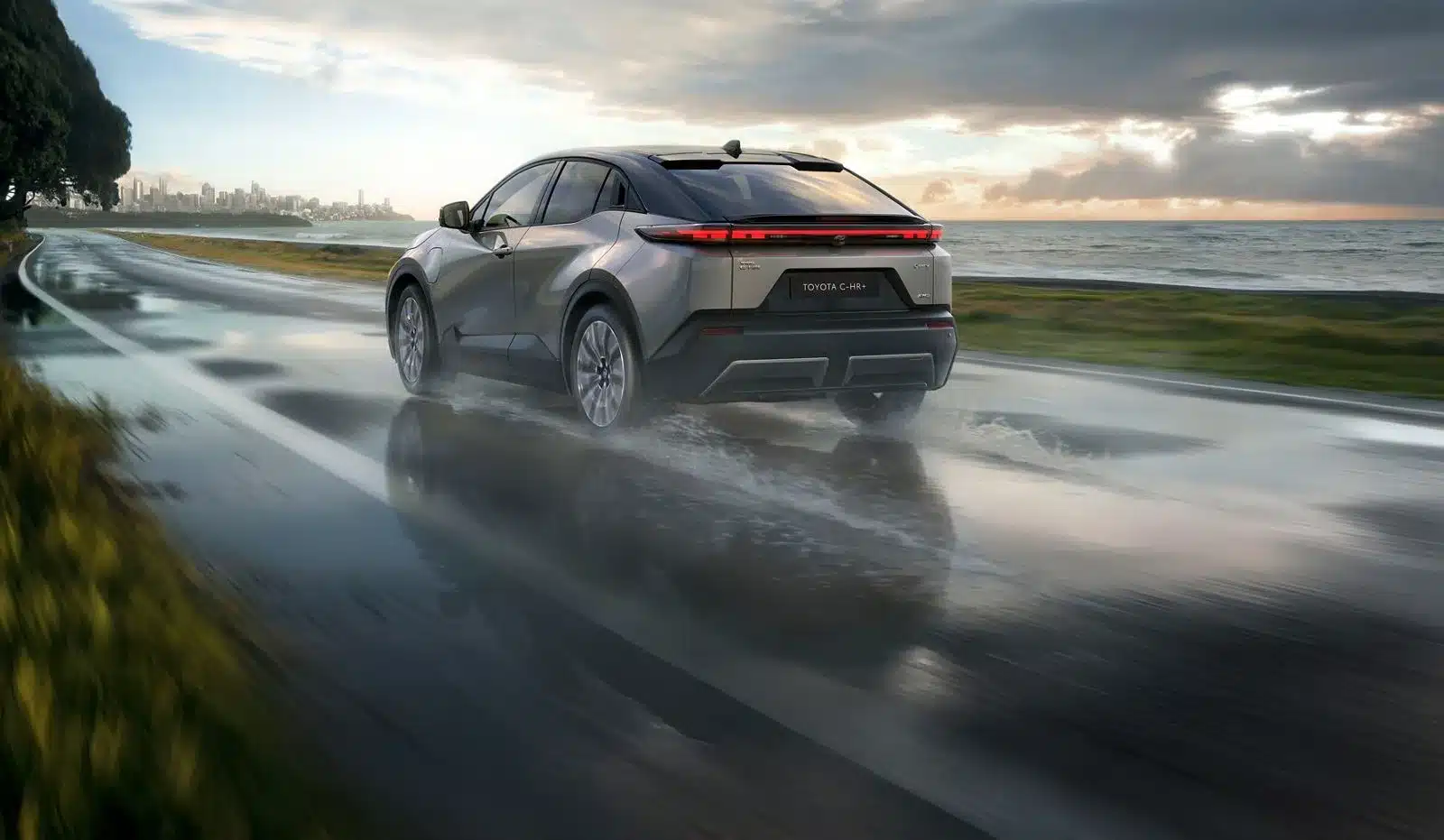Toyota C-HR+ Heckansicht bei Regen auf nasser Straße an der Küste