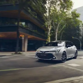 Toyota Corolla Hybrid, silber, fährt in moderner Stadtlandschaft.