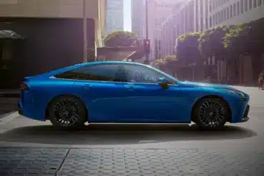Seitenansicht des blauen Toyota Mirai, einer wasserstoffbetriebenen Limousine, in einer modernen Stadt.
