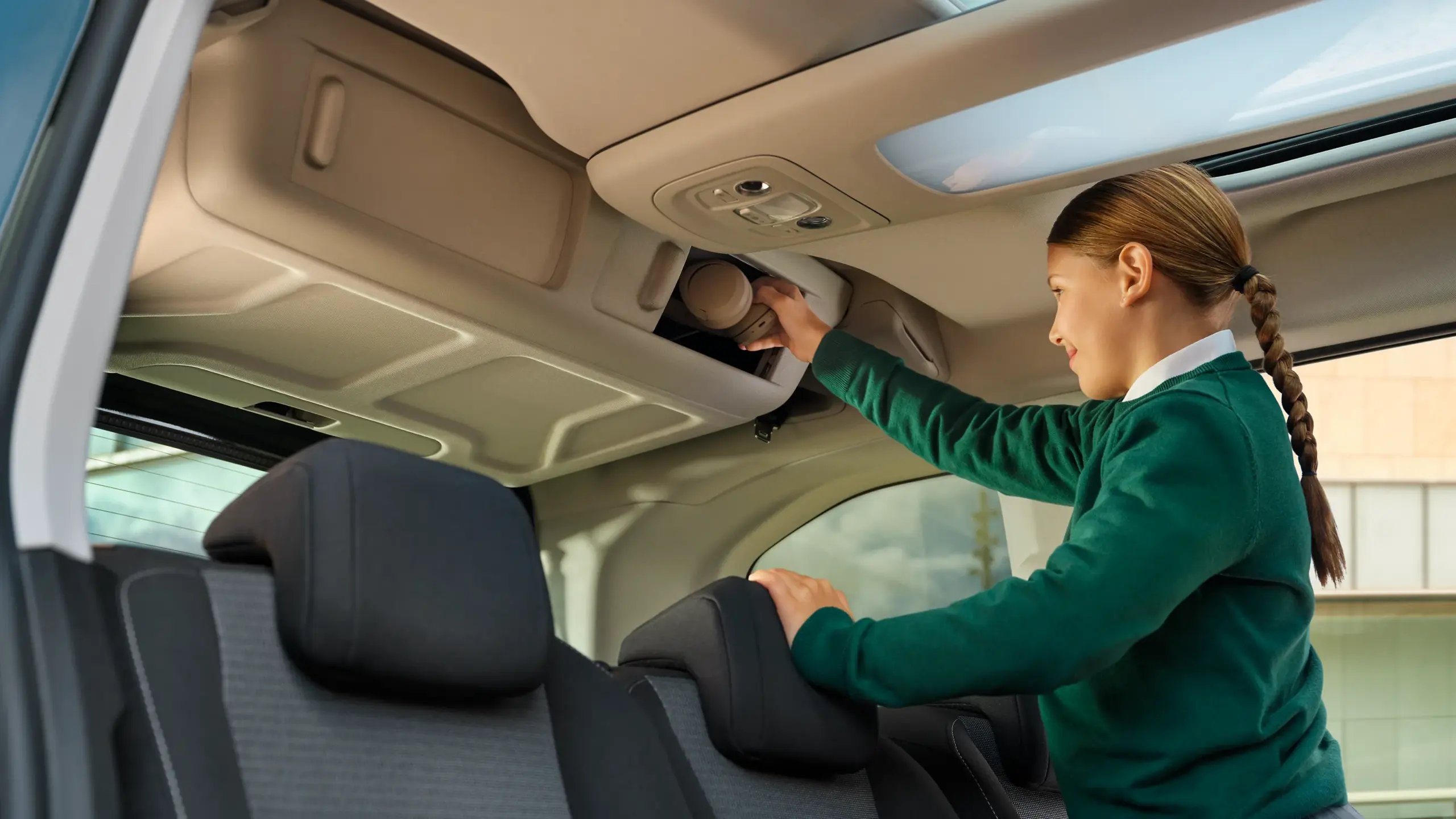 Frau greift nach einem Gegenstand in die Dachablage eines Toyota Proace City Verso mit Panorama-Glasdach.