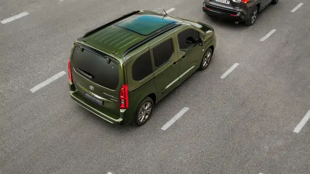 Toyota Proace City Verso in Grün mit Panoramadach von oben auf einer Straße, Rückansicht