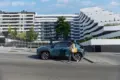 Frau geht auf einen Toyota Yaris Cross zu, der vor einer zeitgenössischen Wohnanlage parkt.