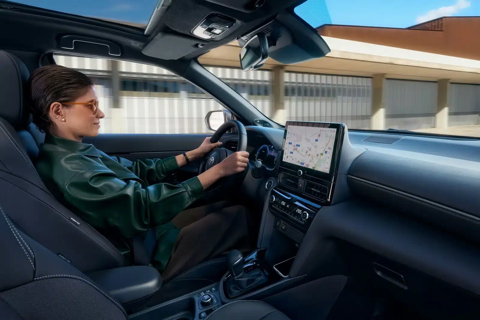 Eine Frau fährt im Innenraum eines Toyota Yaris Cross. Im Vordergrund sind das 12,3-Zoll-Digitaldisplay und der Touchscreen sichtbar.
