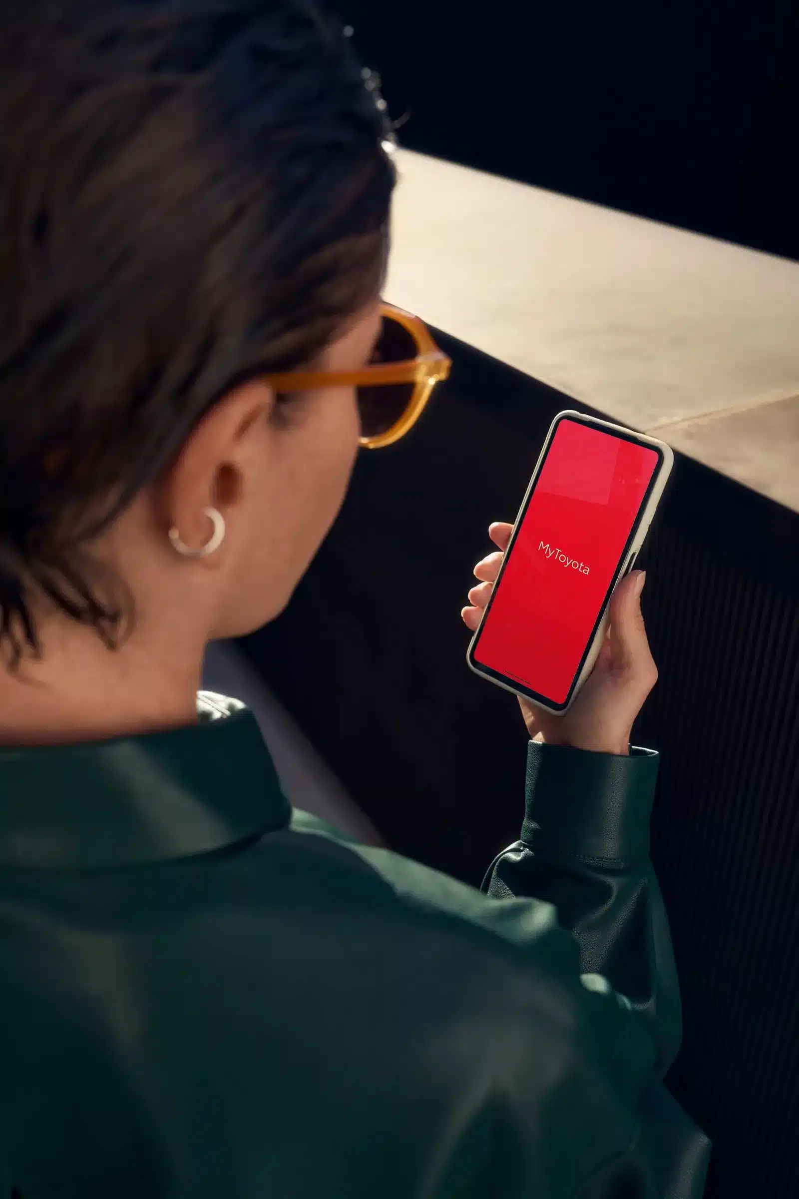 Frau hält ein Smartphone mit der geöffneten MyToyota App in der Hand.