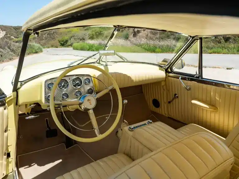 Innenraum und Armaturenbrett eines 1952 Muntz Jet mit beigem Leder und klassischen Rundinstrumenten.