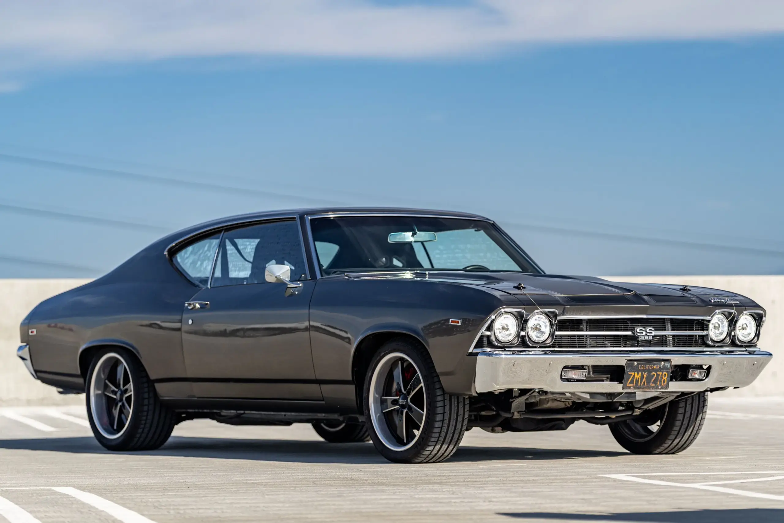 Ein schwarzer Chevrolet Chevelle Malibu 1969 in Seitenansicht auf einem Parkplatz, typisch für das stilvolle Design der späten 1960er US-Automobilgeschichte.
