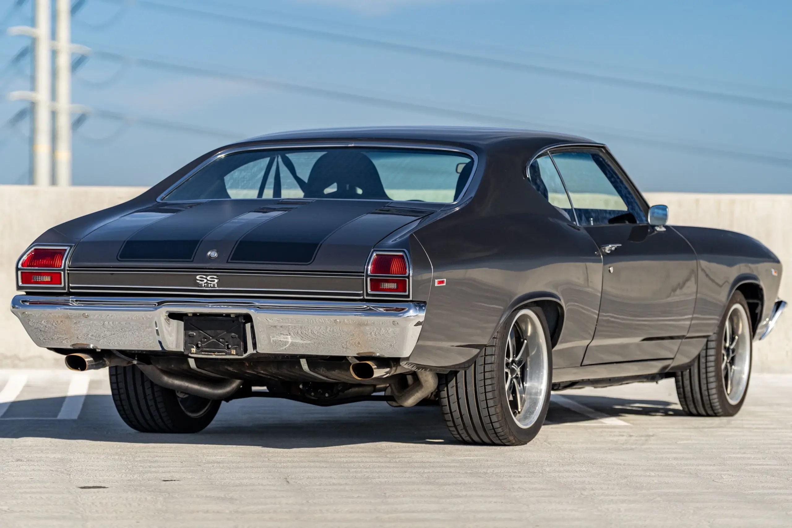 Heckansicht eines klassischen Chevrolet Chevelle Malibu von 1969 in dunkler Lackierung, geparkt auf einem Parkdeck.