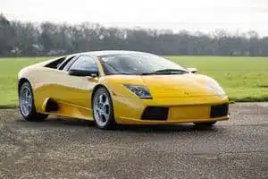 Gelber Lamborghini Murciélago 2002, stehend auf Asphalt vor einer grünen Wiese