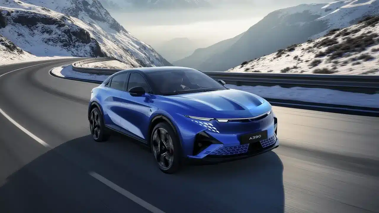 Blauer Alpine A390 fährt sportlich durch eine Kurve in den schneebedeckten Alpen.