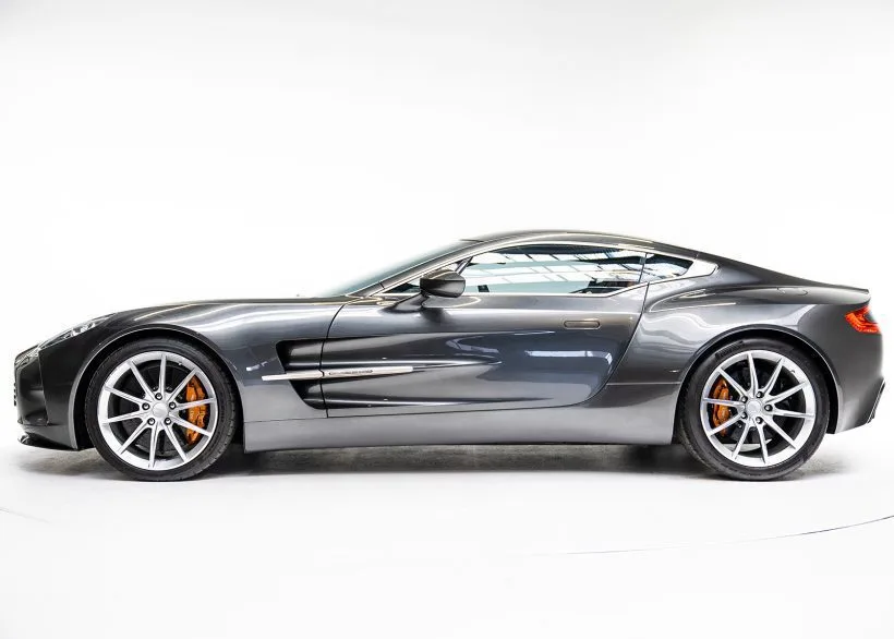 Aston Martin One-77 seitlich fotografiert auf weißem Hintergrund, silbergraue Karosserie, Supersportwagen der Extraklasse.