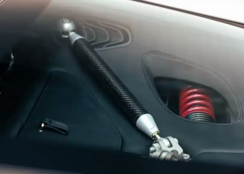 Nahaufnahme einer Carbonstrebe und eines roten Fahrwerksfederbeins im Aston Martin One-77