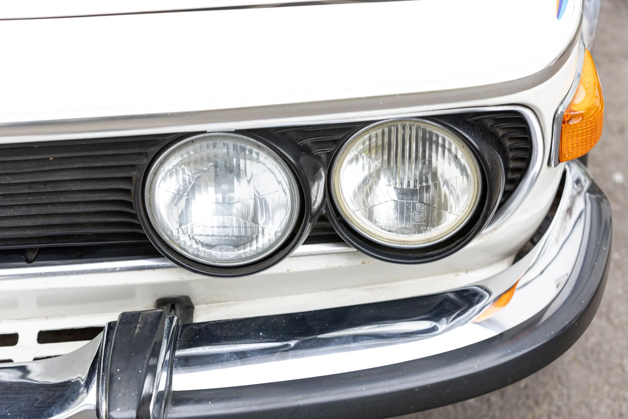 Nahaufnahme der Frontscheinwerfer und Stoßstange eines weißen BMW 3.0 CSL aus den 1970er Jahren