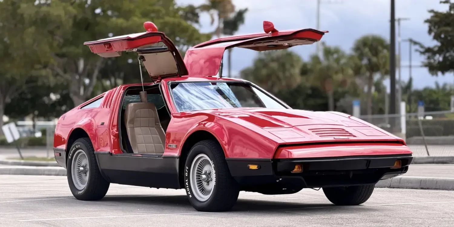 Bricklin SV-1, rotes Sportcoupé von 1975 mit offenen Flügeltüren auf einem Parkplatz, Seitenansicht.