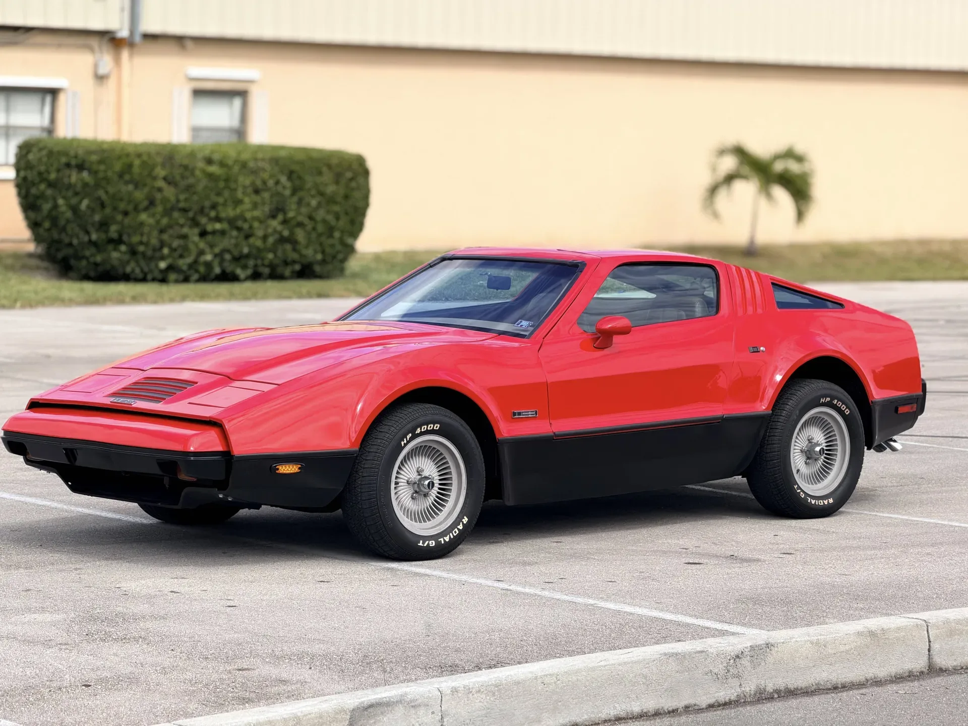 Seitenansicht eines roten Bricklin SV-1 Coupés von 1975, geparkt auf einem Parkplatz.
