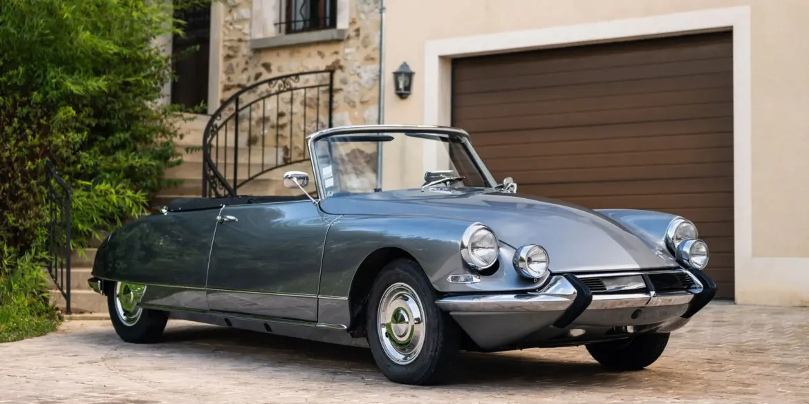 Citroën DS21 Cabriolet aus dem Jahr 1966 in Grau, seitliche Frontansicht, geparkt vor einem Haus