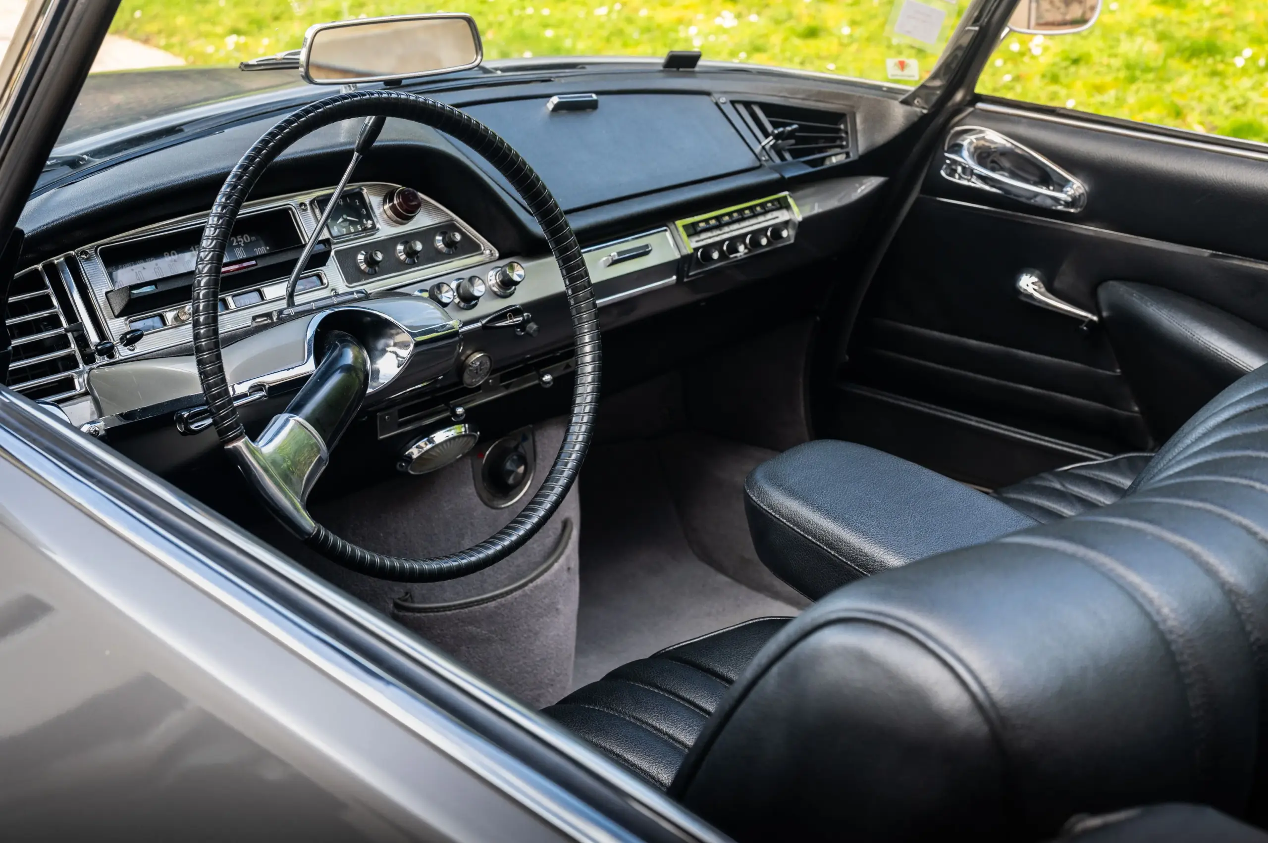 Innenansicht eines Citroën DS21 Cabriolets von 1966 mit Blick auf Lenkrad, Armaturenbrett und schwarze Ledersitze.
