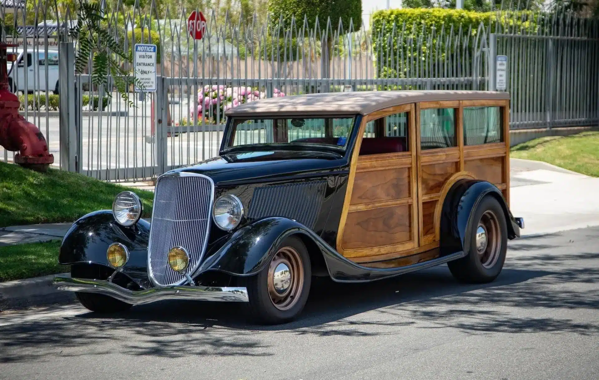 Seitenansicht eines 1934 Ford Station Wagon Replica Street Rods mit Holzkarosserie und schwarzen Kotflügeln, geparkt auf der Straße in einer Stadt.