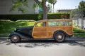 Seitliche Gesamtaufnahme eines 1934 Ford Station Wagon Replica Street Rod mit Karosserie aus Mango- und Koa-Holz, geparkt am Straßenrand bei Tageslicht