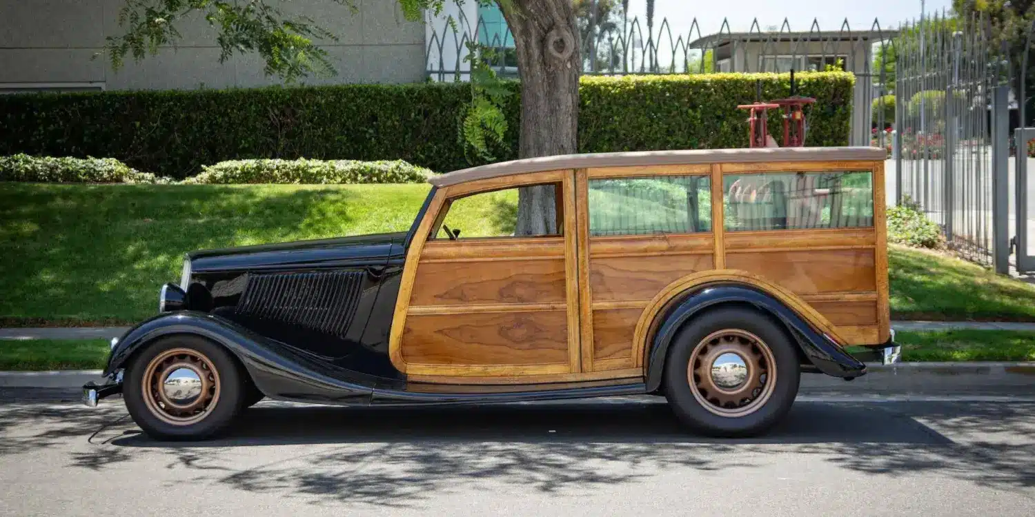 Seitliche Gesamtaufnahme eines 1934 Ford Station Wagon Replica Street Rod mit Karosserie aus Mango- und Koa-Holz, geparkt am Straßenrand bei Tageslicht