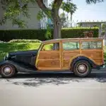 Seitliche Gesamtaufnahme eines 1934 Ford Station Wagon Replica Street Rod mit Karosserie aus Mango- und Koa-Holz, geparkt am Straßenrand bei Tageslicht