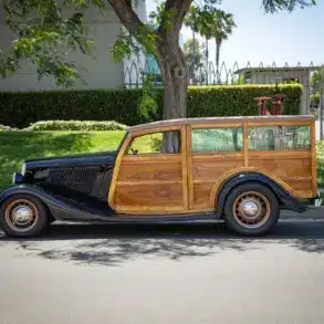 Seitliche Gesamtaufnahme eines 1934 Ford Station Wagon Replica Street Rod mit Karosserie aus Mango- und Koa-Holz, geparkt am Straßenrand bei Tageslicht