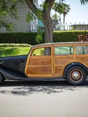 Seitliche Gesamtaufnahme eines 1934 Ford Station Wagon Replica Street Rod mit Karosserie aus Mango- und Koa-Holz, geparkt am Straßenrand bei Tageslicht