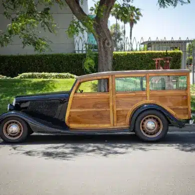 Seitliche Gesamtaufnahme eines 1934 Ford Station Wagon Replica Street Rod mit Karosserie aus Mango- und Koa-Holz, geparkt am Straßenrand bei Tageslicht