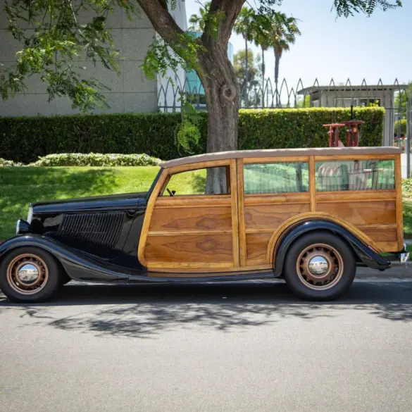 Seitliche Gesamtaufnahme eines 1934 Ford Station Wagon Replica Street Rod mit Karosserie aus Mango- und Koa-Holz, geparkt am Straßenrand bei Tageslicht