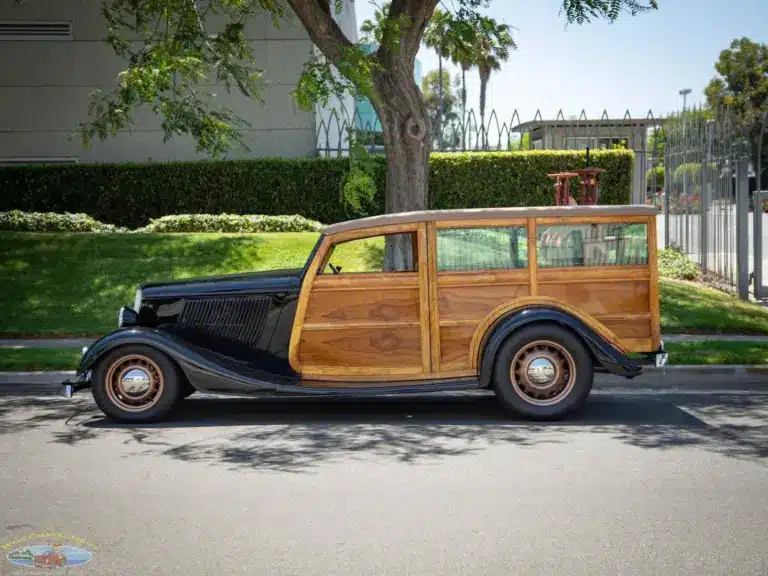 Seitliche Gesamtaufnahme eines 1934 Ford Station Wagon Replica Street Rod mit Karosserie aus Mango- und Koa-Holz, geparkt am Straßenrand bei Tageslicht