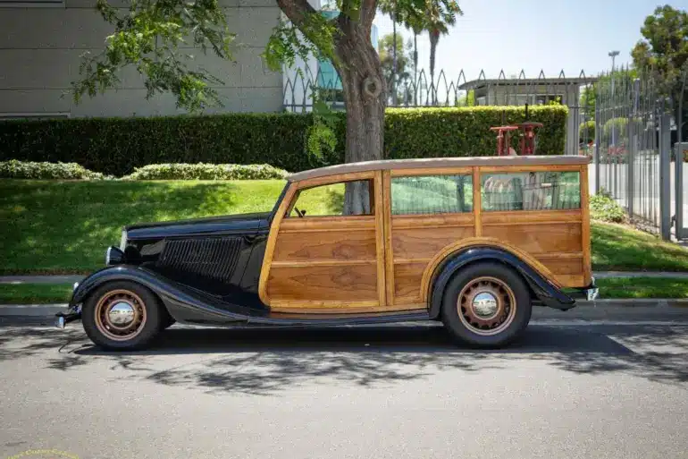 Seitliche Gesamtaufnahme eines 1934 Ford Station Wagon Replica Street Rod mit Karosserie aus Mango- und Koa-Holz, geparkt am Straßenrand bei Tageslicht