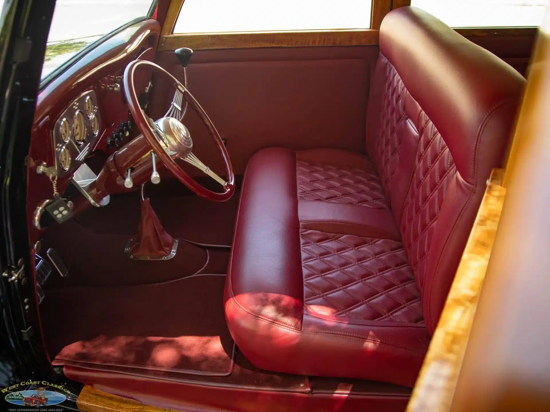 Innenraum mit roter Lederausstattung und Banjo-Lenkrad eines 1934 Ford Station Wagon Replicas, Sicht auf Sitzbank und Holzelemente