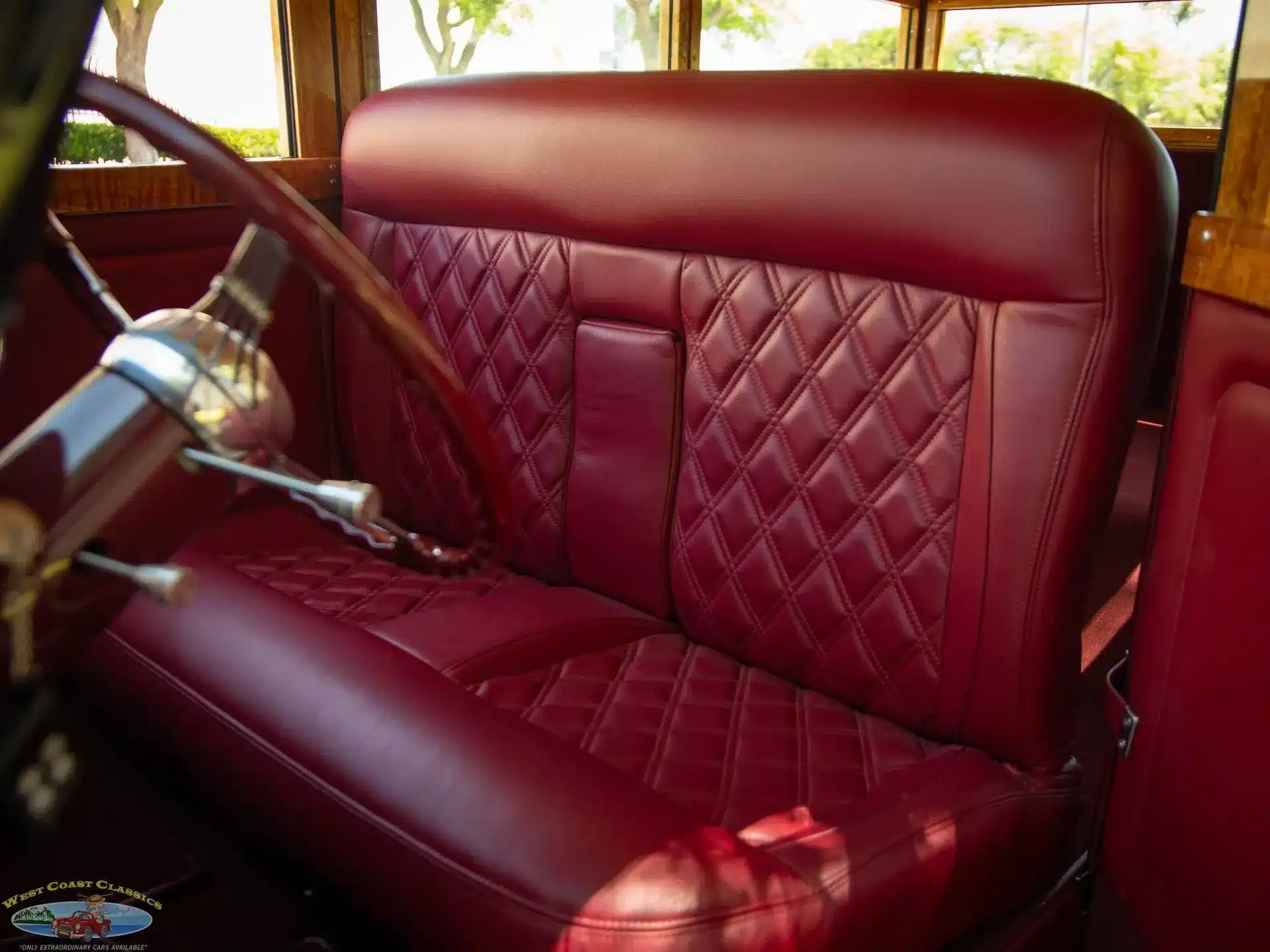 Rote, diamantgesteppt ausgeführte Ledersitzbank im Innenraum eines 1934 Ford Station Wagon Replica Street Rods mit klassischem Lenkrad.