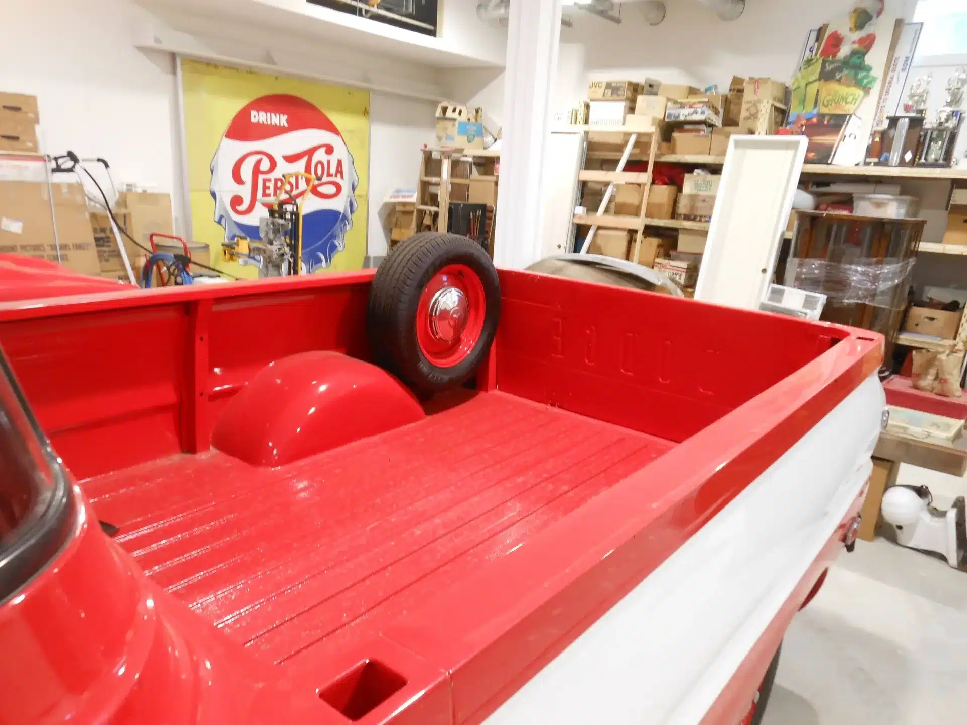 Rote Ladefläche eines Dodge A100 Pickups von 1970 mit montiertem Ersatzrad in einer Werkstatthalle