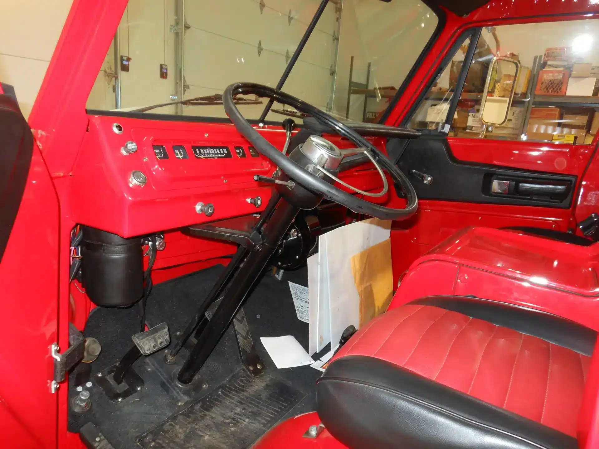 Restaurierter Innenraum eines Dodge A100 Pickup von 1970 mit rotem Armaturenbrett und schwarzem Lenkrad.