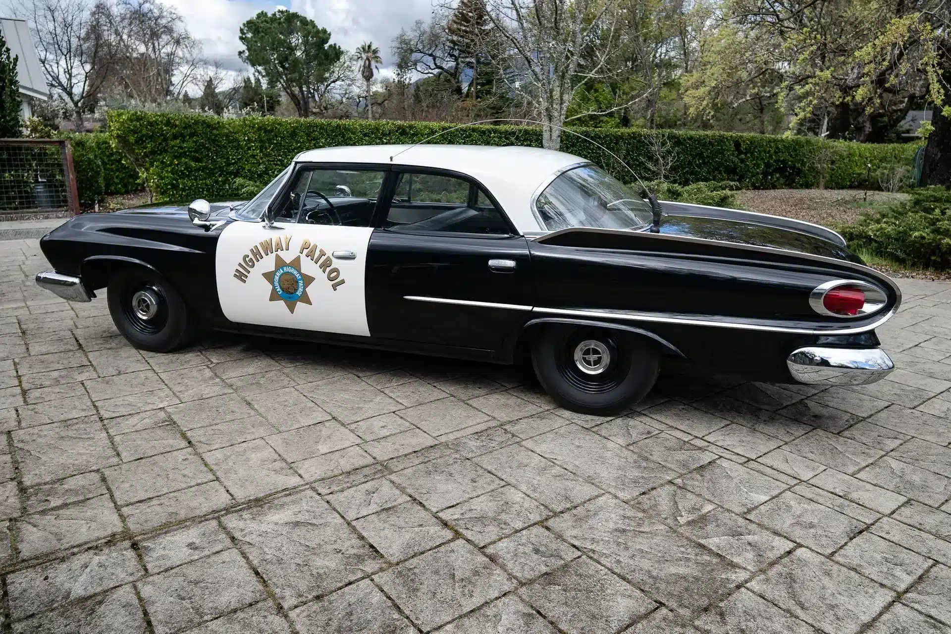 Klassischer Dodge Polara 1961 als originales Highway Patrol Police Car mit markanten Heckflossen, schwarz-weißer Lackierung und typischen Polizeiemblemen.
