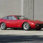 Roter Ferrari 365 GTC/4 aus dem Jahr 1972, geparkt vor einer Ziegelmauer.