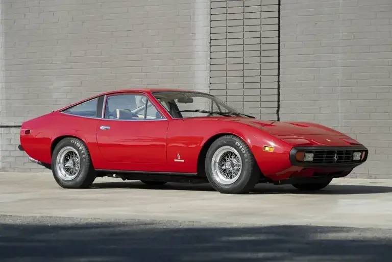 Roter Ferrari 365 GTC/4 aus dem Jahr 1972, geparkt vor einer Ziegelmauer.