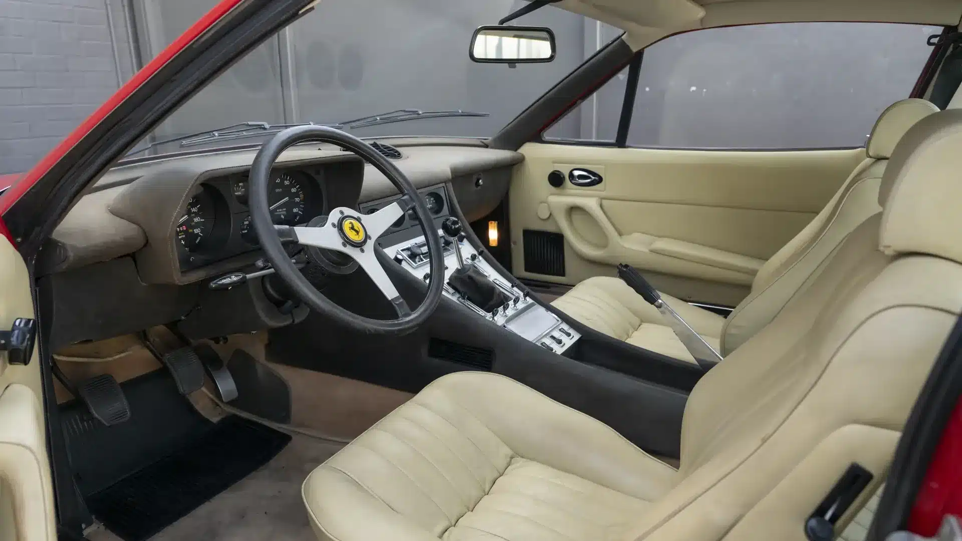 Der Innenraum eines Ferrari 365 GTC/4 aus dem Jahr 1972 mit beigem Leder, Schaltgetriebe und charakteristischem Ferrari-Lenkrad.