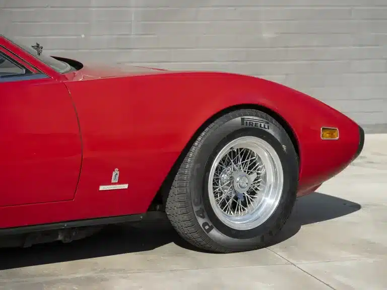 Frontpartie eines Ferrari 365 GTC/4 in Rosso Cherry, klar erkennbar sind Lack, Vorderrad und Pininfarina-Emblem