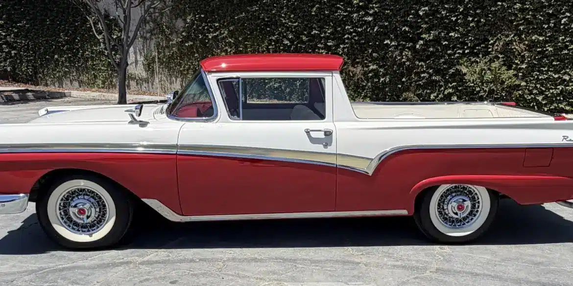 Seitenansicht eines restaurierten Ford Ranchero von 1957 in Rot und Weiß, geparkt auf einem Asphaltplatz.