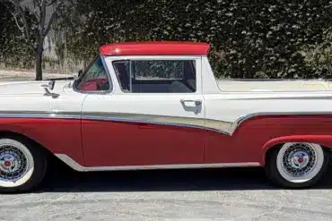 Seitenansicht eines restaurierten Ford Ranchero von 1957 in Rot und Weiß, geparkt auf einem Asphaltplatz.