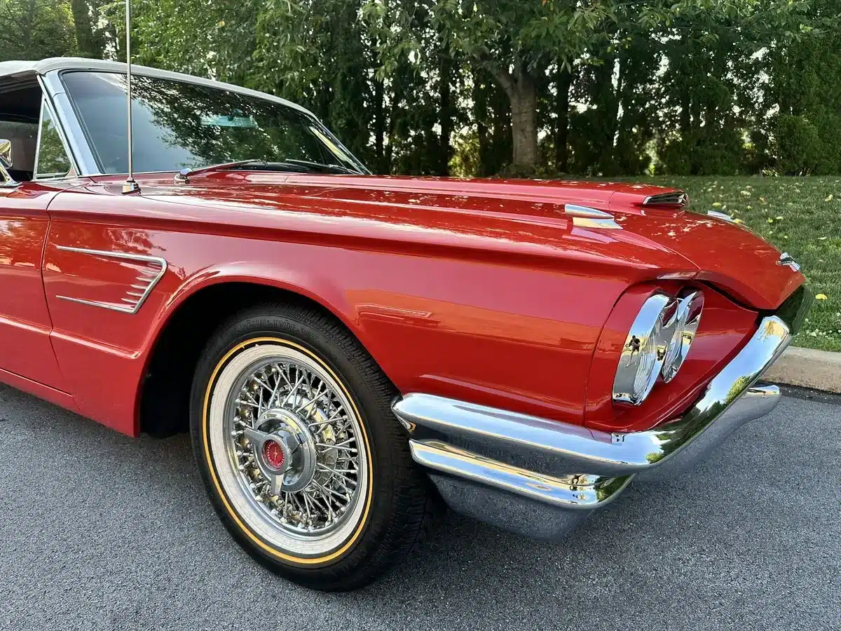 Frontansicht eines roten Ford Thunderbird Cabriolets aus dem Jahr 1965 mit Drahtspeichenrad und typischem Chromzierrat.