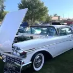 1957 Mercury Monterey Coupé in Classic White und Sunset Orchid mit geöffneter Motorhaube, vorgeführt auf einer Oldtimer-Ausstellung.