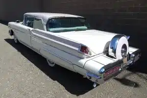 1957 Mercury Monterey Coupé, zweifarbig in Classic White und Sunset Orchid, mit großzügigen Heckflossen und auffälligem Ersatzrad.