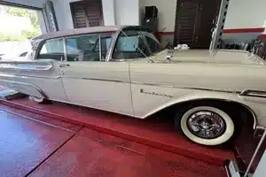 Seitliche Ansicht eines Mercury Monterey Coupés von 1957 in Classic White und Sunset Orchid mit Weißwandreifen in einer Garage